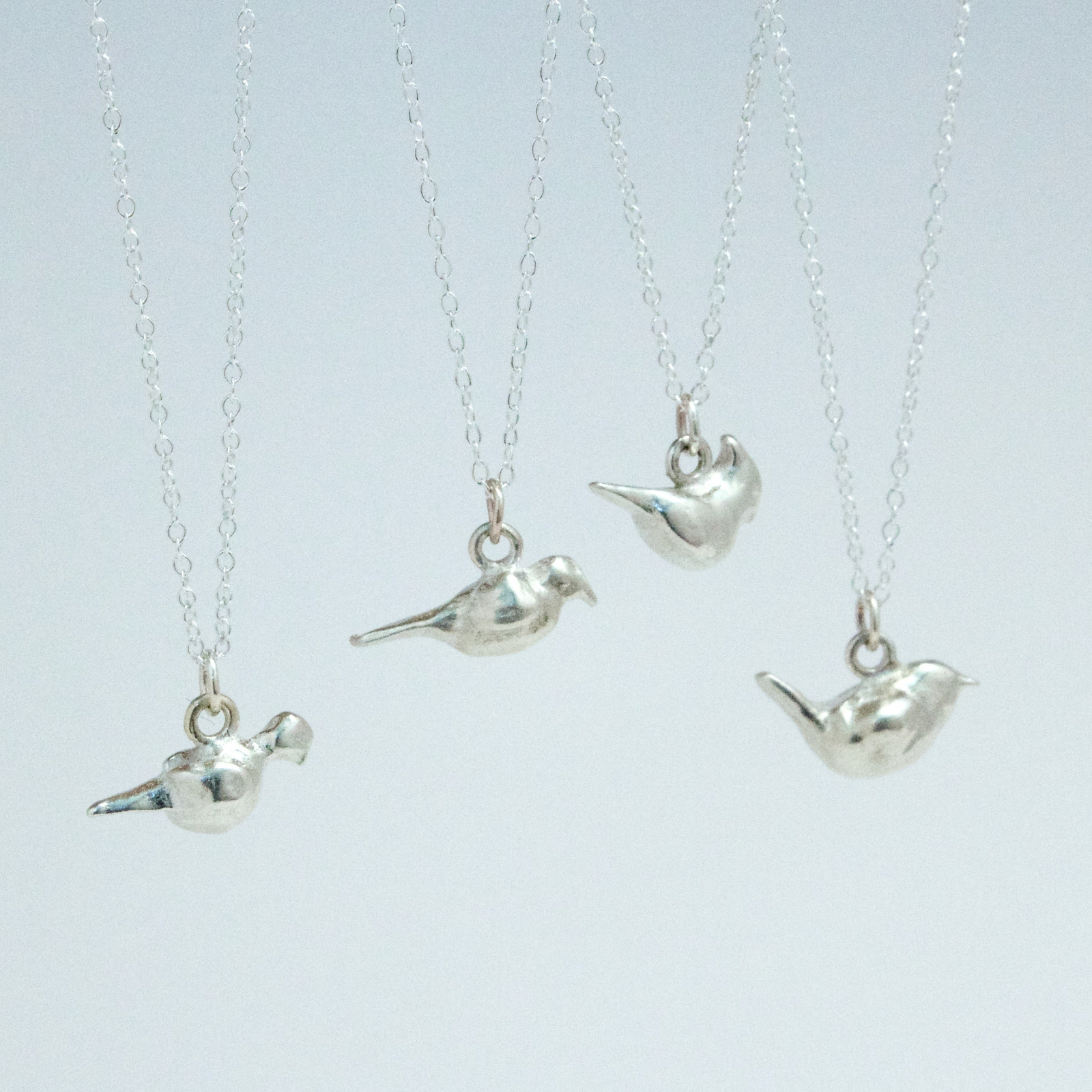 4 sterling silver bird charms arranged hanging & cropped in