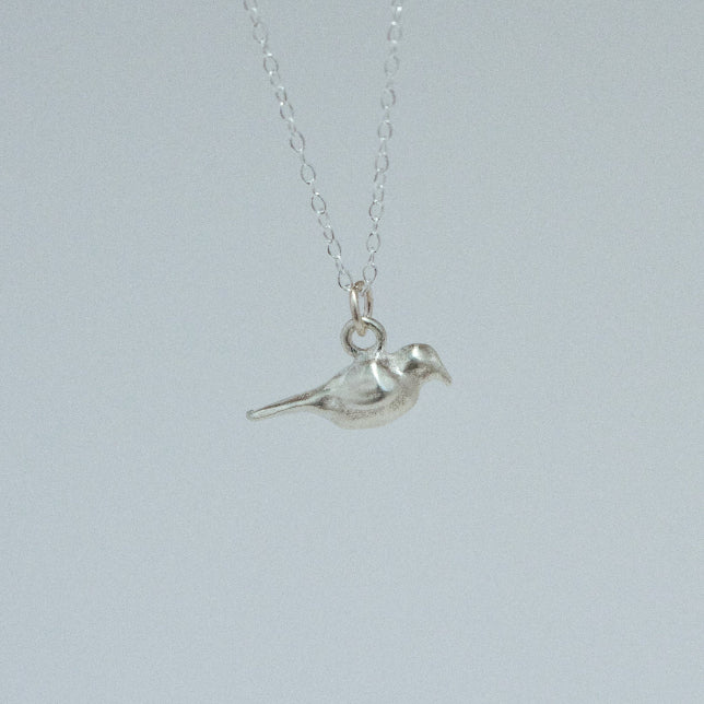 product image of a sterling silver crow charm on a chain necklace facing right