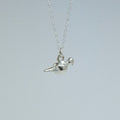 Silver bird pendant necklace on a light gray background