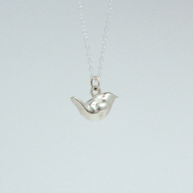 product image of a sterling silver wren charm on a chain necklace facing right, almost backwards